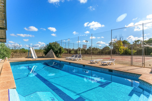 Fantastischer Poolbereich mit Sonnenliegen neben dem Tennisplatz